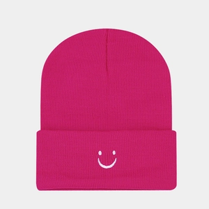 Detailed view of magenta knitted beanie featuring a white embroidered smile face