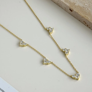 Detail of gold necklace featuring zircon-encrusted heart pendants and fine chain link
