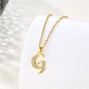 Detailed view of an 18K gold letter G pendant with cubic zirconia on a cable chain