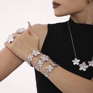 Elegant silver stainless steel flower jewelry set featuring rings and bracelets on model