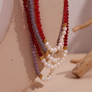Detailed close-up of multilayer beaded necklace with red crystal and freshwater pearls