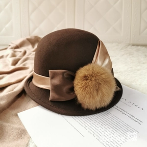 Detail of coffee brown wool felt hat with satin ribbon bow and fuzzy pompom accessory