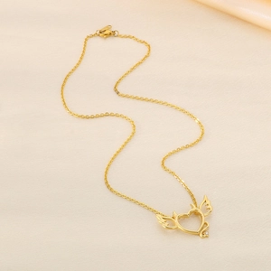 Macro detail of gold-plated heart pendant with angel wings and small diamond inlay