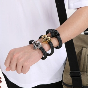 Close-up of braided leather bracelets with gold, silver and black skull metal charms
