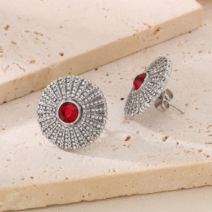Detail of silver round sunburst stud earrings with red center stone and white crystals