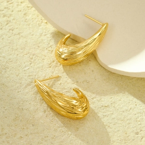 Minimalist gold stainless steel C-shaped earrings with textured pattern in warm studio light