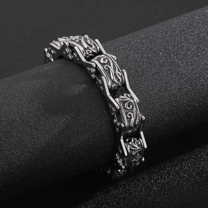 Detail of vintage floral engraving on masculine stainless steel X-shaped link bracelet