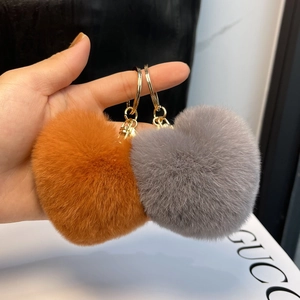 Detail of soft heart-shaped fur keychains in orange and grey with golden metal rings