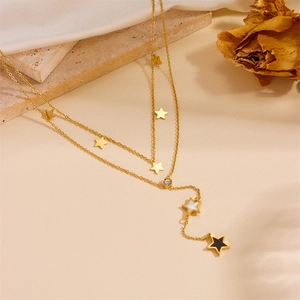 Detail of gold double-layer necklace with star pendants and white mother-of-pearl