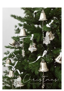 Detail of metal Christmas bells and snowflake pendants hanging on a festive tree branch