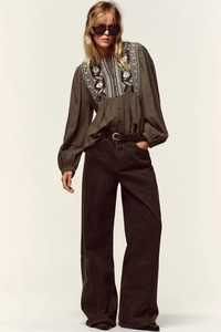 Detail of ethnic embroidery and textured fabric on bohemian olive long sleeve blouse