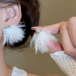 Dettaglio di orecchini a piuma d'argento con nappe indossati da una modella
