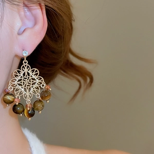 Detailed close-up of vintage gold filigree drop earrings with tiger eye beads and zircon