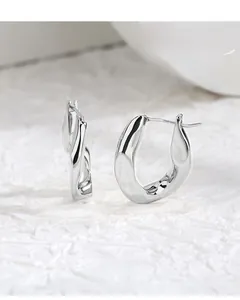 Macro detail of minimalist silver oval earrings with metallic texture and organic curves