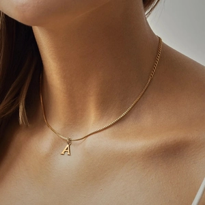Minimalist gold stainless steel A-letter pendant necklace worn on woman's collarbone