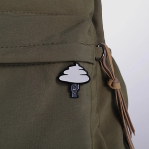 Cute black and white cloud enamel pin badge on olive green backpack surface