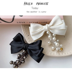 Detail of satin bow hair clips with pearls and metallic beads on a soft pink book