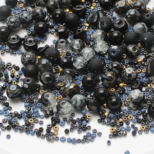 Macro detail of mixed black and grey glass beads with golden accents for DIY jewelry