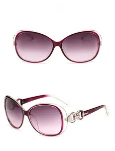Detail of oversized sunglasses showing gradient burgundy lenses and gold chain temples