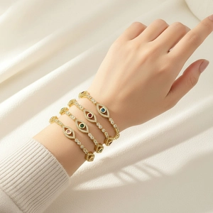 Detailed close-up of stacked evil eye bracelets with colorful zircon stones in gold finish