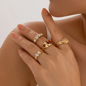 Detailed view of gold rings set with red gemstones and pearls on model fingers