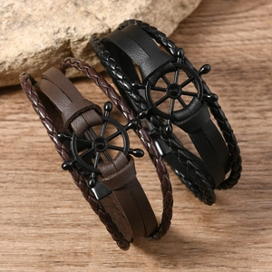 Handmade woven leather bracelets in black and brown with vintage rudder charm on wood