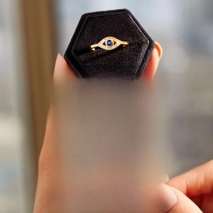 Detail of s925 gold evil eye ring with blue crystal on a black velvet jewelry box