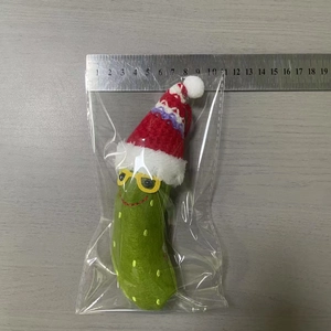 Detailed size measurement of a green crochet pickle wearing a red Santa hat next to a ruler