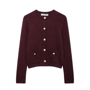 Detail of burgundy knit cardigan with gold embossed buttons and symmetrical pockets