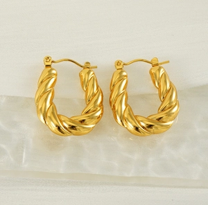 Detailed close-up of 18k gold-plated twisted U-shape hoop earrings on white fabric