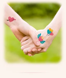 Close-up of glitter heart tattoo stickers with pink and red designs on hand