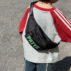 Kids black waist bag with green PATYR letters and adjustable strap shown on model back