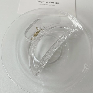 Macro detail of transparent acrylic hair claw clip with golden metal spring mechanism