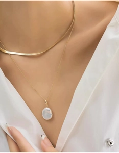 Close-up of double-layered gold snake chain necklace with baroque pearl pendant