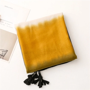 Detail of yellow gradient scarf with long black tassels and breathable textured fabric