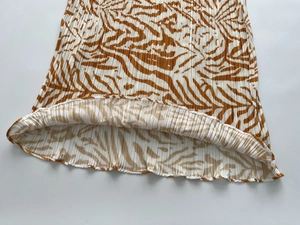 Macro detail of brown and beige zebra pattern on pleated plissé fabric with wavy hem