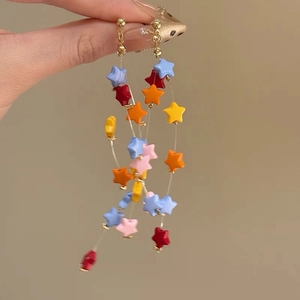 Detailed close-up of long dangling earrings with colorful star-shaped beads in vibrant hues