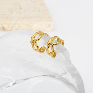 Macro detail of gold-plated double-layer interwoven wave ear cuff on textured glass