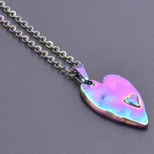 Macro shot of 18k plated rainbow heart pendant with embossed detail on link chain