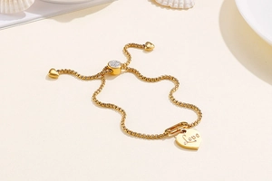Detail of adjustable gold heart bracelet with Love engraving and cubic zirconia slider