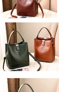 Close-up of brown and green crocodile pattern bucket bags with premium metal locks