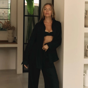 Detailed view of women's black three-piece lounge set with shirt, top, and wide-leg trousers