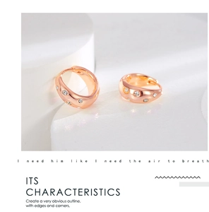 Macro detail of wide rose gold hoop earrings with white zircon crystals and mirror finish