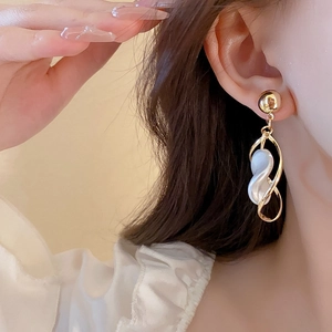 Elegant gold twisted star earrings with pearls worn by a model in a close-up shot