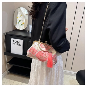 Detail view of pink floral embroidery, gold metal frame, and red tassel on the crossbody bag