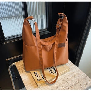 Detail of caramel nylon tote bag with Fashion patch on a marble surface background