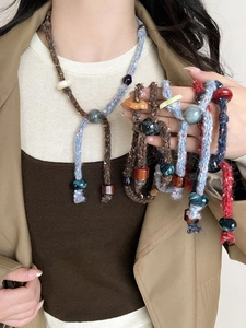 Close-up of handmade bohemian woven necklace with resin beads on a model wearing a blazer