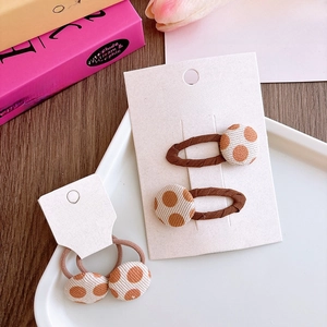 Detalle de set de tres piezas de pinzas y gomas para el pelo con flores café con leche