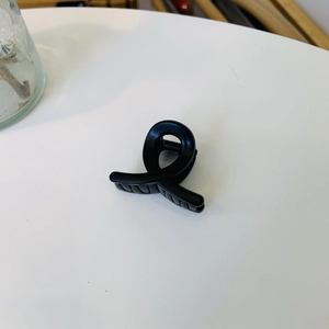 Detailed macro view of matte black cross shark clip with anti-slip comb teeth