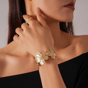 Detail of gold floral cuff bracelet and matching ring on model with textured petals